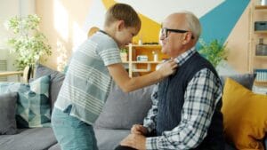 Little boy helping a senior button his shirt